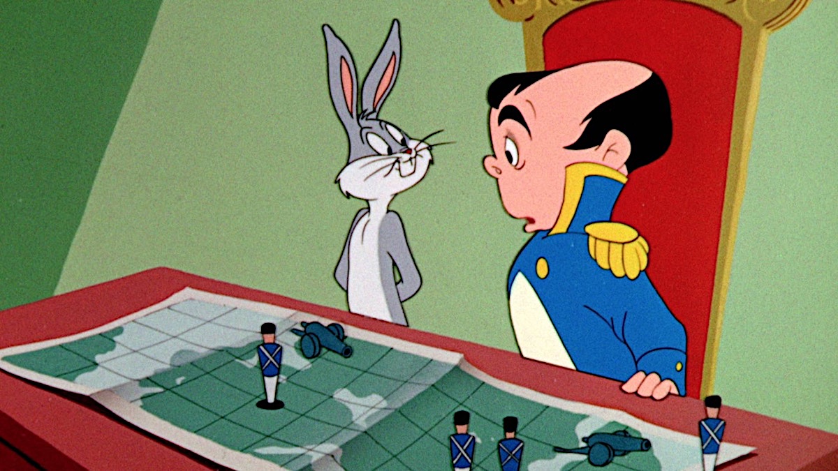 Bugs Bunny stands next to Napoleon as they look at a strategy map featuring various model soldiers and cannons in the 1956 short “Napoleon Bunny-Part”