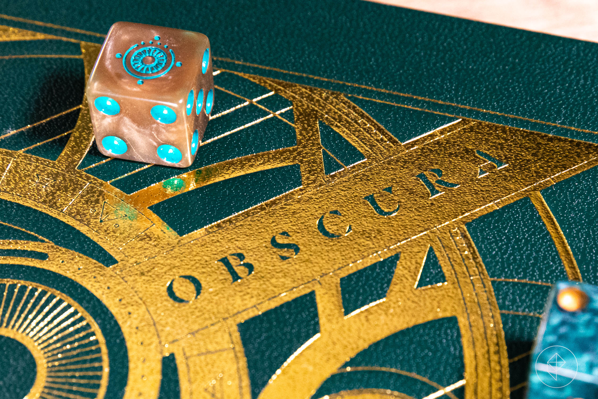 A die from Candela Obscura rests atop the gilded cover of the leatherette collector’s edition.