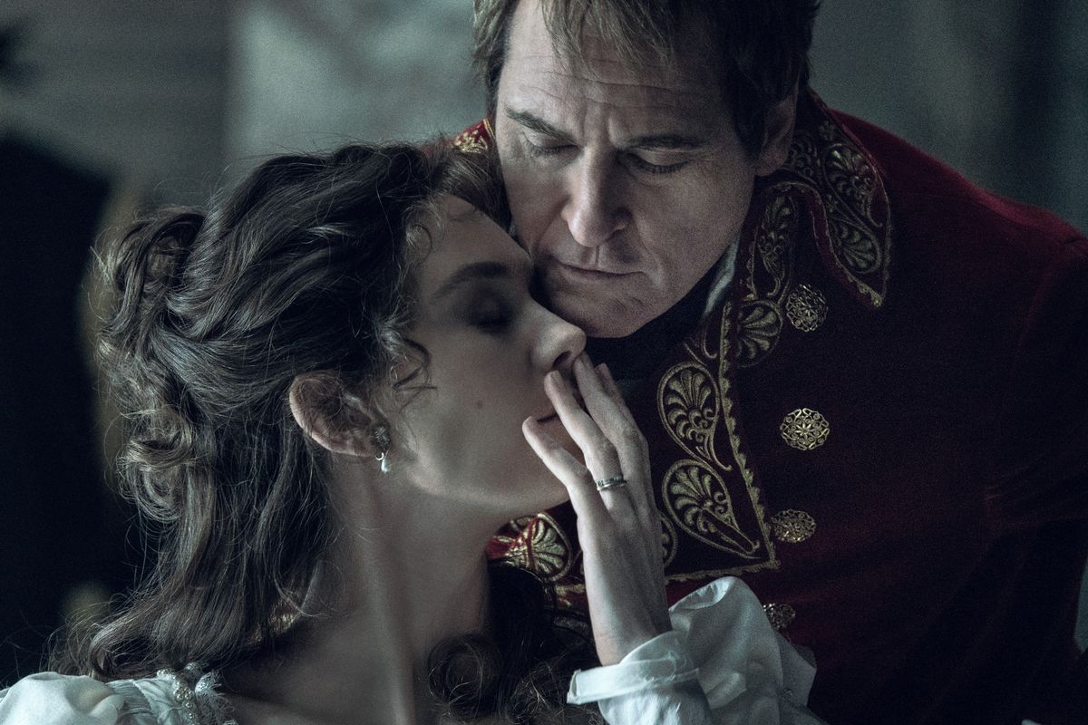 Napoleon Bonaparte leans forward over his wife Josephine’s face, who is turning to the side with her mouth covered by her hand in the film Napoleon.